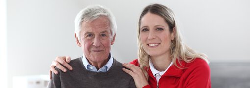 Pflegerin und älterer Mann lächeln in die Kamera | © Heinz von Heydenhaber